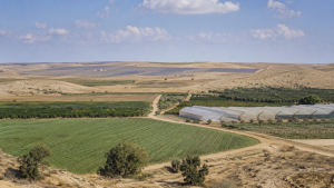 שטחים חקלאיים במושבי הנגב עם שדות, חממות ומתקני אנרגיה סולארית ברקע